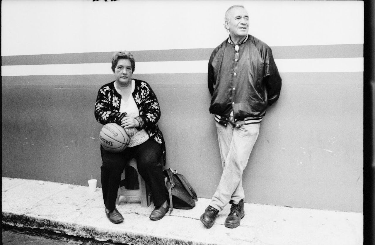 PORTRAIT OF SMILING WOMAN SITTING ON WALL