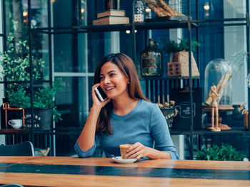 Young woman using phone on table