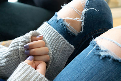 Midsection of woman wearing sweater sitting at home