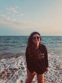 Beautiful woman standing at beach against sky