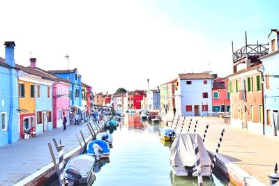 Boats in canal amidst buildings in city against sky