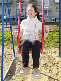 Full length of girl sitting on swing at playground