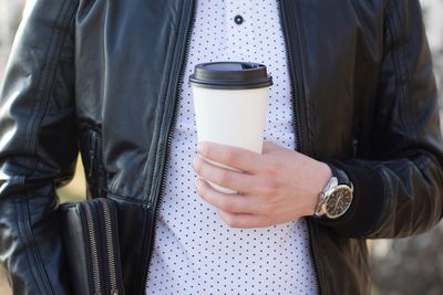 Midsection of man holding disposable cup