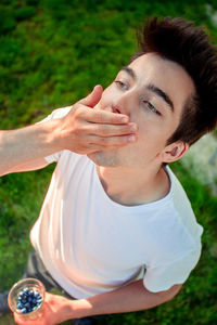 High angle view of teenage boy eating blueberries while standing on field