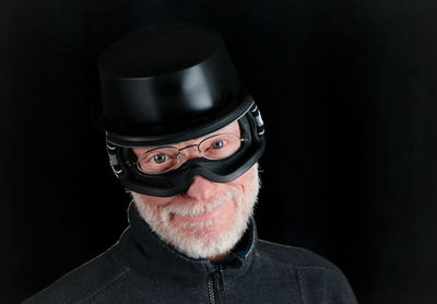 Portrait of man wearing funny hat and glasses against black background