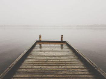 Pier over lake against sky during winter