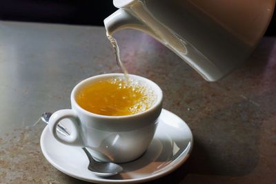 Herbal tea pouring in cup on table