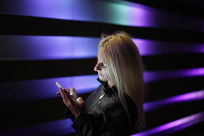 Woman standing by illuminated wall