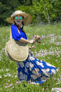 Portrait of woman with pink flowers on field