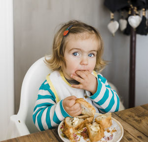 Portrait of baby girl eating food while sitting at table