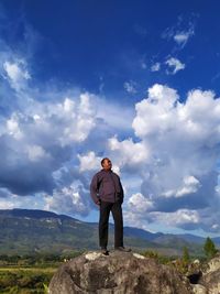 Full length of man standing on rock against sky