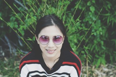 High angle portrait of young woman wearing sunglasses by plants
