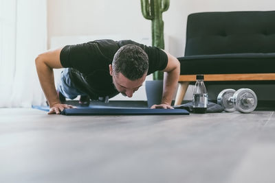 Sporty man working out and trains at home. fit boy doing exercises on the mat in the living room. 