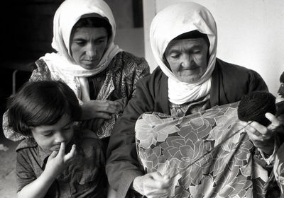 Senior woman with daughter and granddaughter knitting wool at home