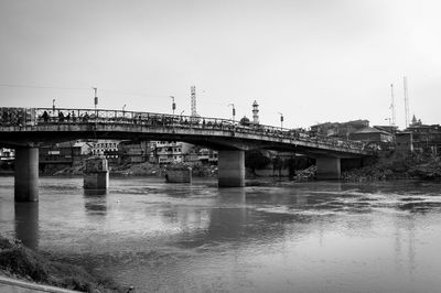 Bridge over river in city against clear sky