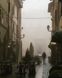 People walking on street amidst buildings during rainy season