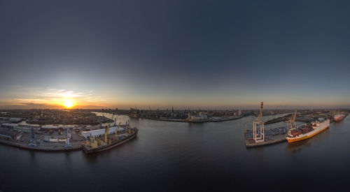 Boats moored in sea against buildings in city during sunset