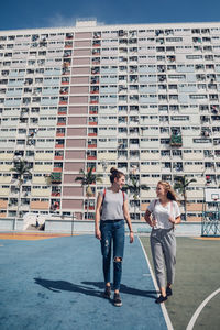 Friends walking against buildings in city