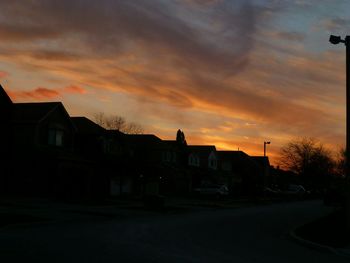 Silhouette houses against sky at sunset