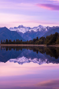 Scenic view of lake and mountains against sky during sunset