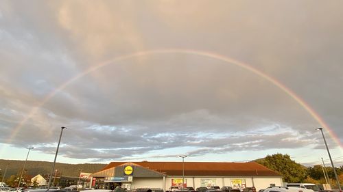 Low angle view of rainbow over buildings against sky