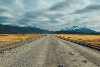 Dirt road amidst landscape against sky