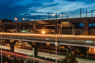 Light trails on bridge in city against sky