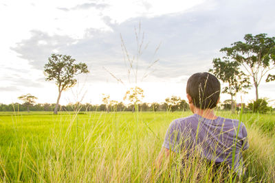 Rear view of man standing on field against sky