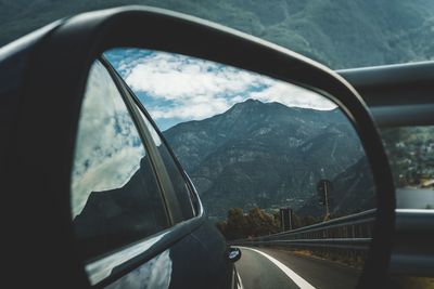 Reflection of mountains in side-view mirror of car