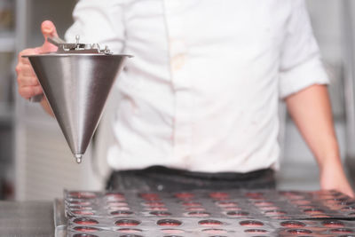 Midsection of man holding ice cream standing on table