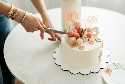 Close-up of a woman's hand cutting a cake during a birthday celebration at home