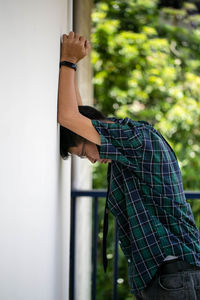 Man standing by window against wall