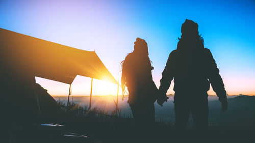 Silhouette people standing against sky during sunset