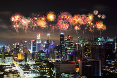 Firework display over illuminated buildings in city at night