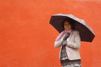 Woman standing against red wall