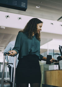 Businesswoman scanning smart phone at check-in counter in airport