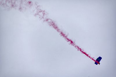 Low angle view of vapor trail and parachute against clear sky