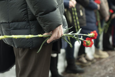 Two carnations in man's hand. details of funeral ceremony. commemorative flowers in hand. 