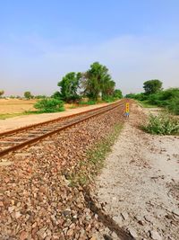 Railroad track amidst field against sky