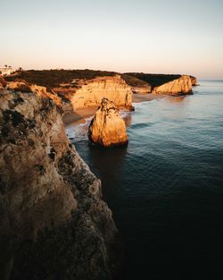 Rock formations by sea against clear sky