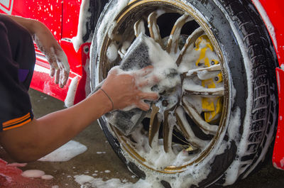 Cropped hands of manual worker cleaning car