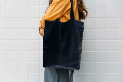 Midsection of woman standing against wall