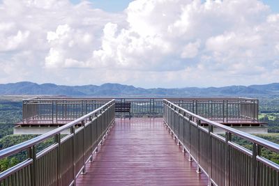 Footbridge over lake against sky