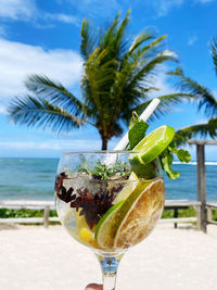 Close-up of wine glass on beach against sky