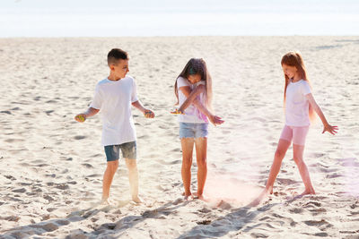 Cute kids playing with powder paint at beach