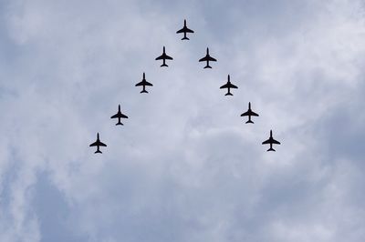 Low angle view of airshow against cloudy sky