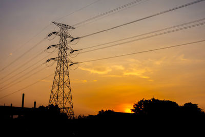 Low angle view of silhouette electricity pylon against sky during sunset