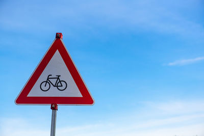 A bicycle traffic sign in front of a blue sky