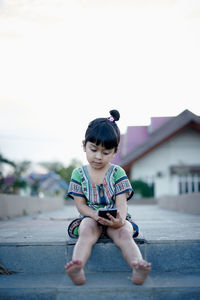 Full length of girl using phone against clear sky