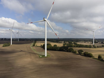 Wind turbines on field against sky